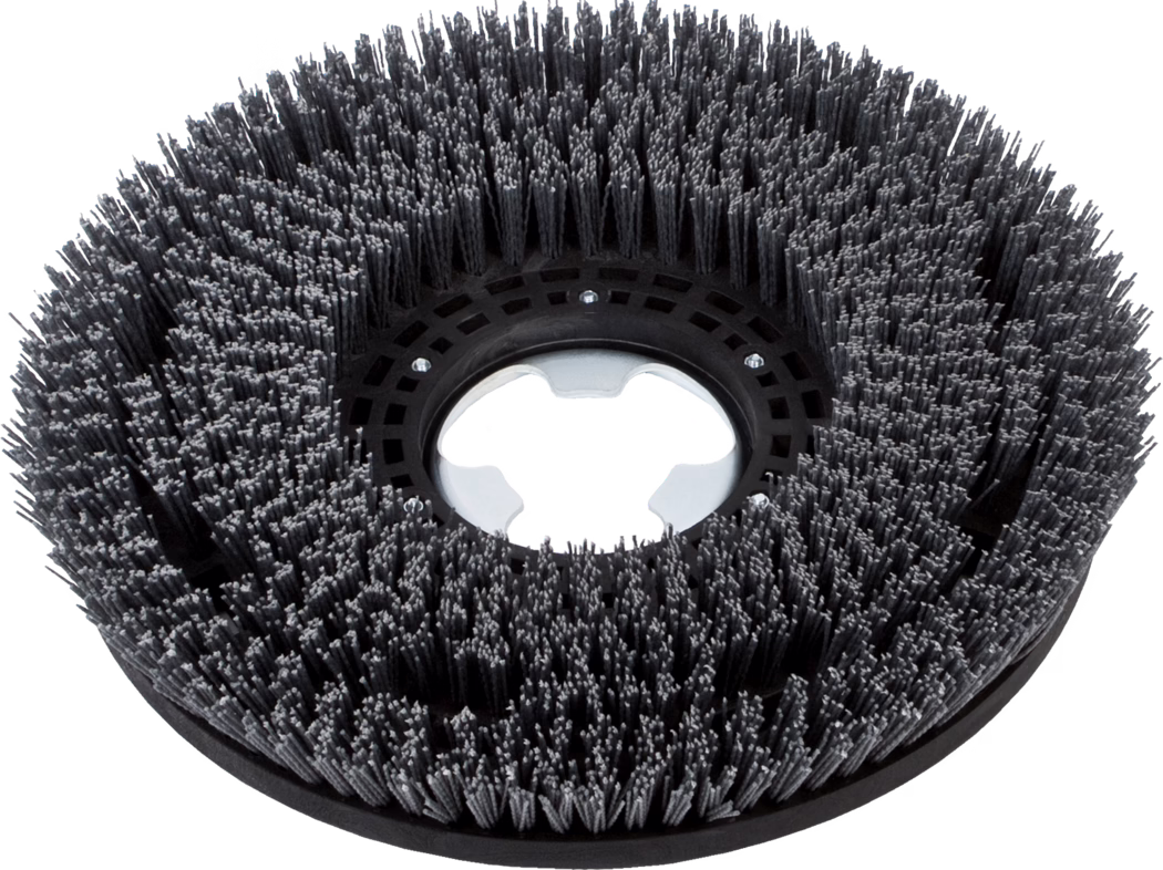 A circular industrial floor scrubbing brush with densely packed dark-gray synthetic bristles arranged in concentric rows, featuring a black plastic central hub with a metal mounting ring, photographed on a white background.