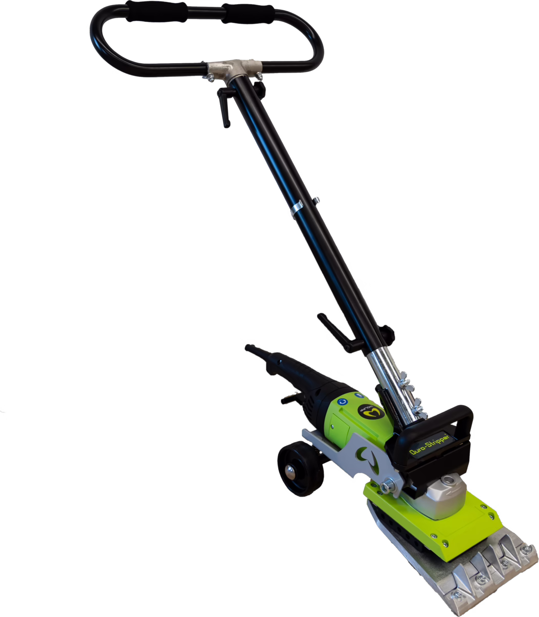 WOLFF_Dummy_84888_Duro Stripper 2.0_2025-08 A powered floor stripping tool photographed on a white background. The device has a long black adjustable tubular handle with foam grips and a height-adjustment clamp, connected to a green and black motor housing mounted on a silver metal chassis with small transport wheels. At the working end there is a rectangular serrated metal scraping plate fixed with bolts and a black protective handguard bearing a printed label; the assembly shows visible fasteners, a pivot/angle joint and a lever for locking the head position. The tool appears designed for removing floor coverings, adhesive residues or tile adhesive in renovation and construction work; materials include painted metal, cast components and plastic housings, and the overall appearance is compact, robust and purpose-built for heavy-duty scraping tasks.
