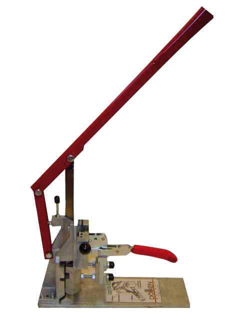 A manual bench press with a long red lever and a small red handgrip mounted on a metal base, used for punching or pressing small parts. The press features a hinged arm, adjustable components, and a rectangular base plate with printed instructions.