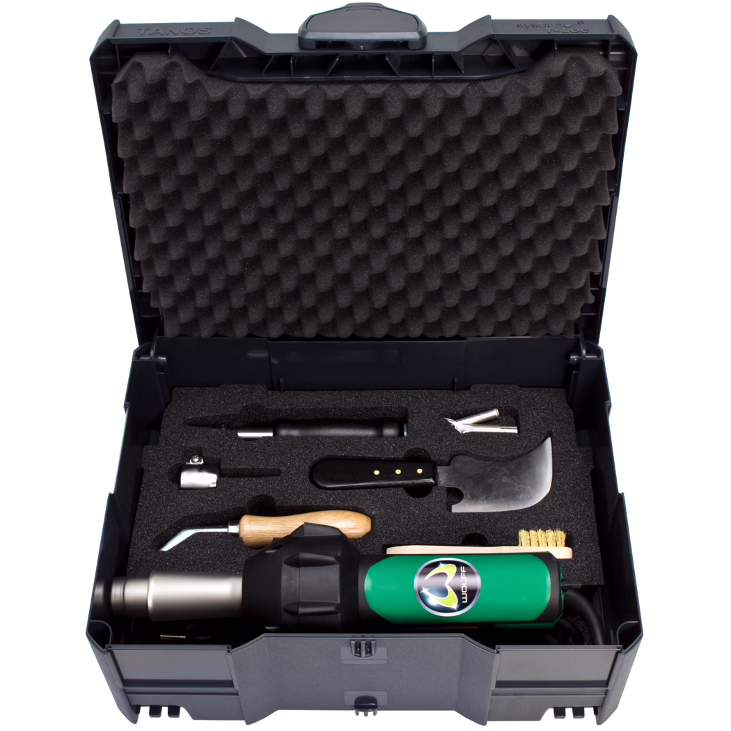 Open hard plastic tool case with egg-crate foam in the lid and custom foam inserts holding a green heat gun and various hand tools such as a curved blade, a wooden-handled tool, metal nozzles and a brass brush.