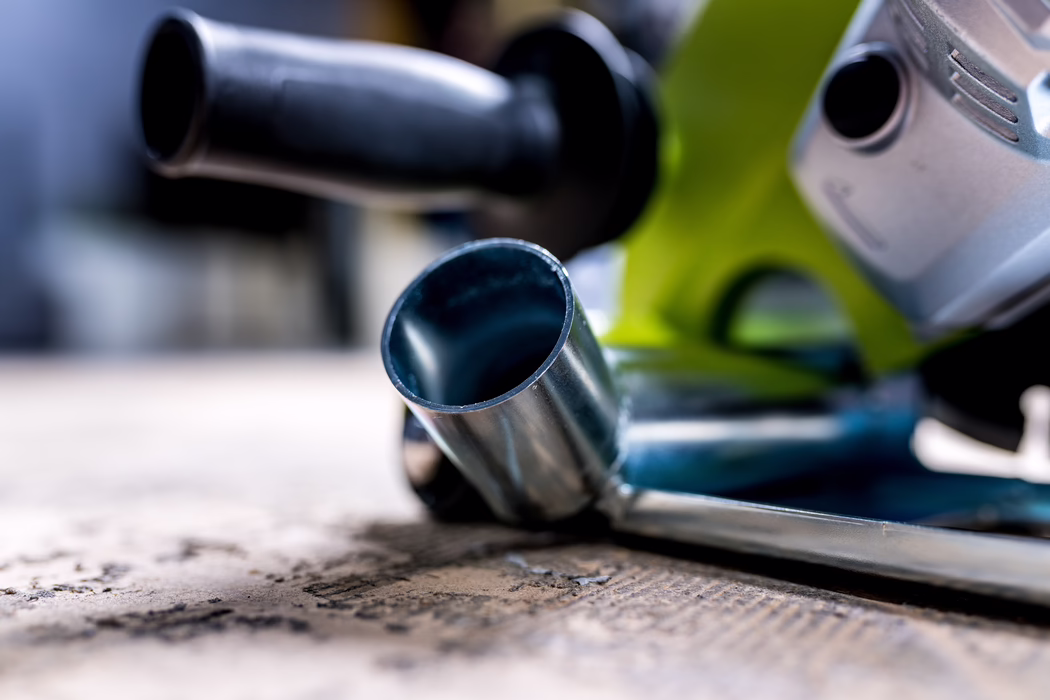 WOLFF_Application Image_18V EF135_Detail2_2022-11 Close-up of a metal socket and hand tool on a textured surface, shallow depth of field showing a cylindrical chrome socket in the foreground and blurred power-tool components (green housing and black handle) in the background.